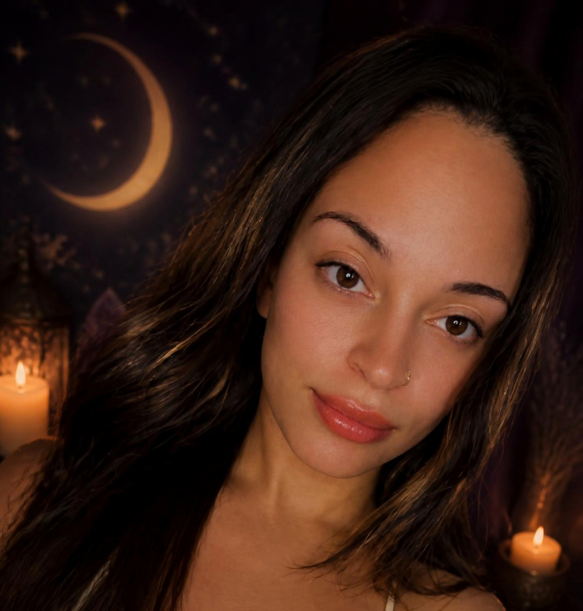 Marie Mystic, tarot reader, in candlelight in front of a crescent moon tapestry